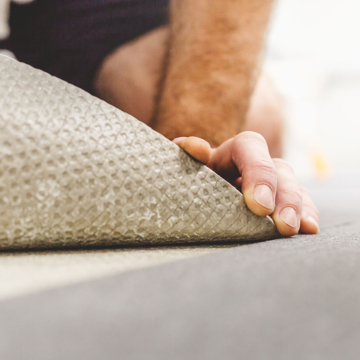 Carpet repair technician lifting carpet edge during professional seam and padding replacement service in San Bernardino