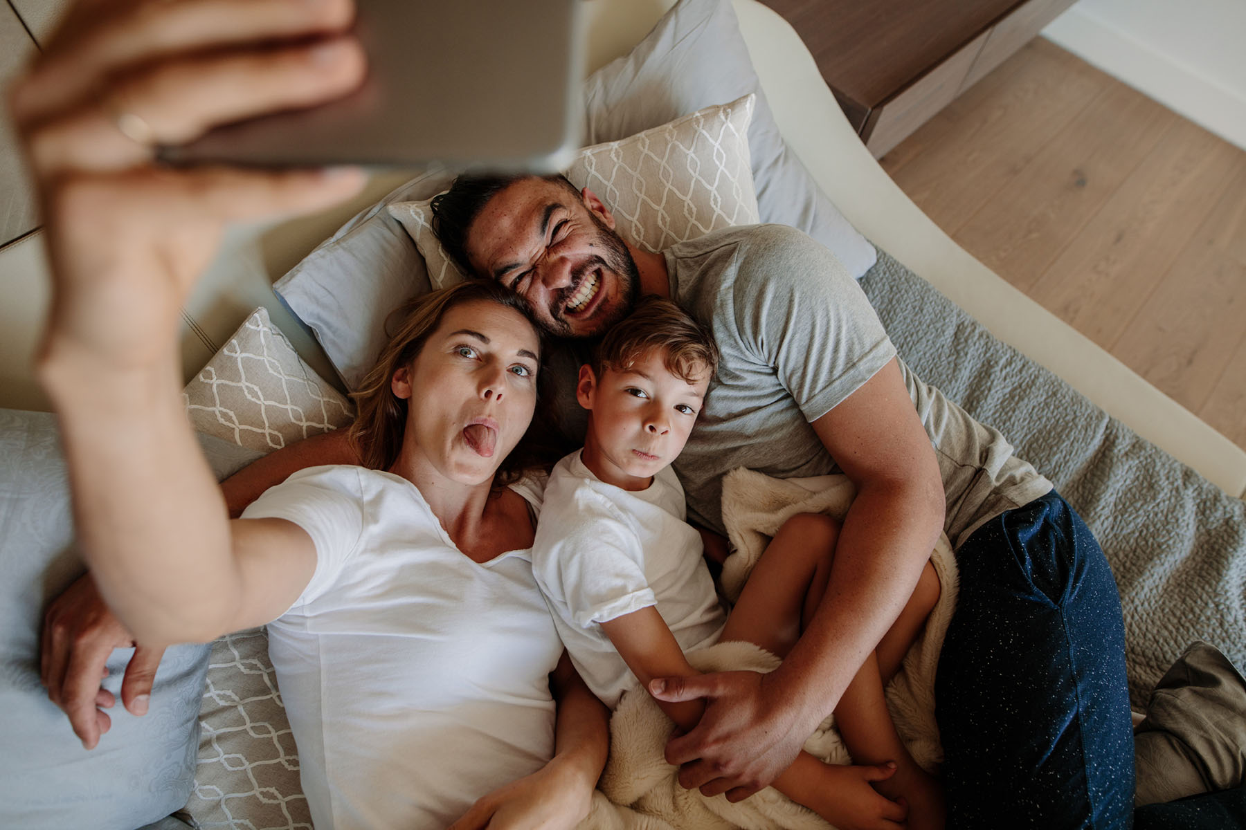 Happy family taking a playful selfie on a bed — Safer Choice Cleaning’s non-toxic, fast-drying upholstery and mattress cleaning for healthy homes.