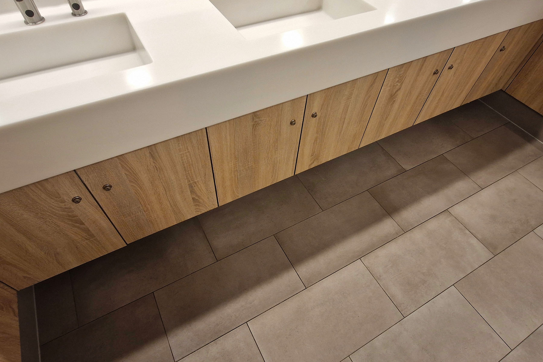 Modern commercial restroom with clean tile floors and wood cabinetry — eco-friendly commercial tile cleaning for offices and facilities in SoCal.