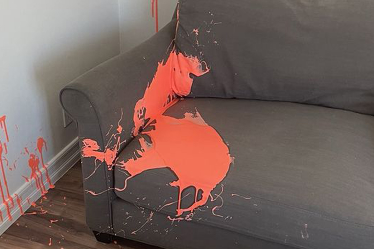Gray couch splattered with orange paint and wall stains — deep upholstery cleaning and stain rescue services near me.