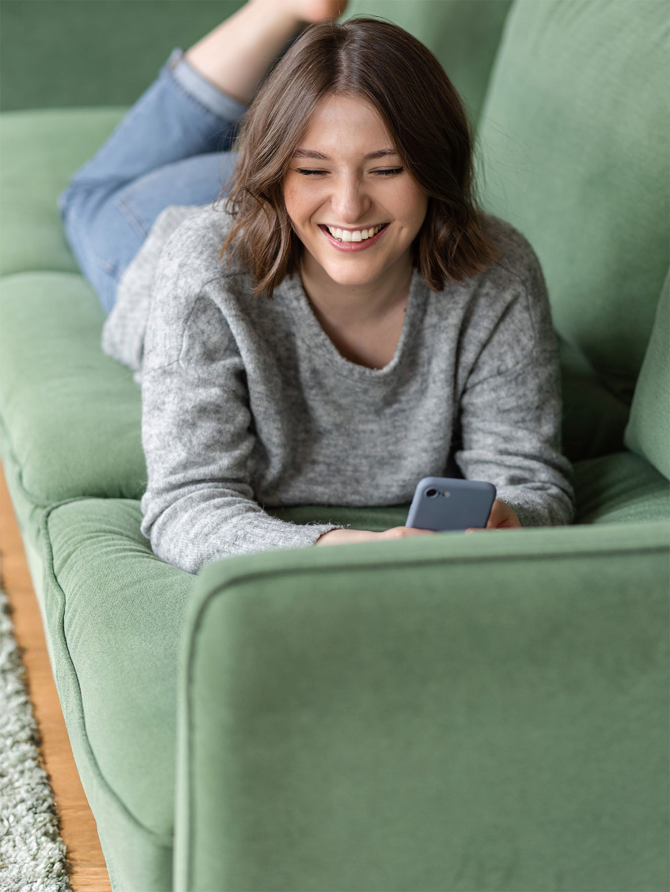 Happy woman relaxing on a freshly cleaned green sofa, showcasing Safer Choice Cleaning’s eco-friendly upholstery cleaning services in Orange County.