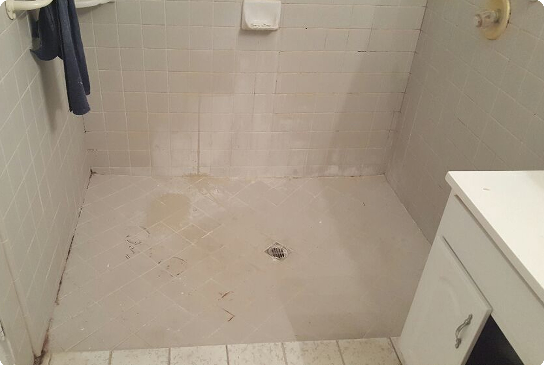 Stained and discolored tile floor and shower wall with moldy grout lines before professional deep cleaning in Orange County.
