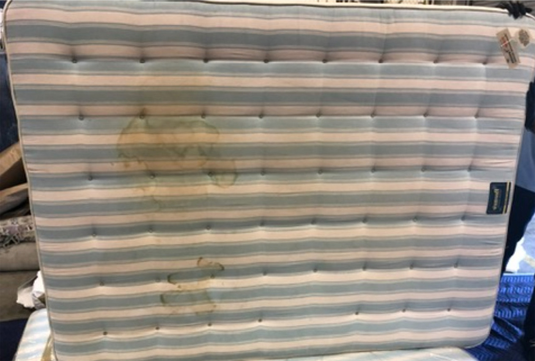 Old striped mattress with deep yellow urine stains—prior to non-toxic mattress cleaning service in Riverside County by Safer Choice Cleaning.